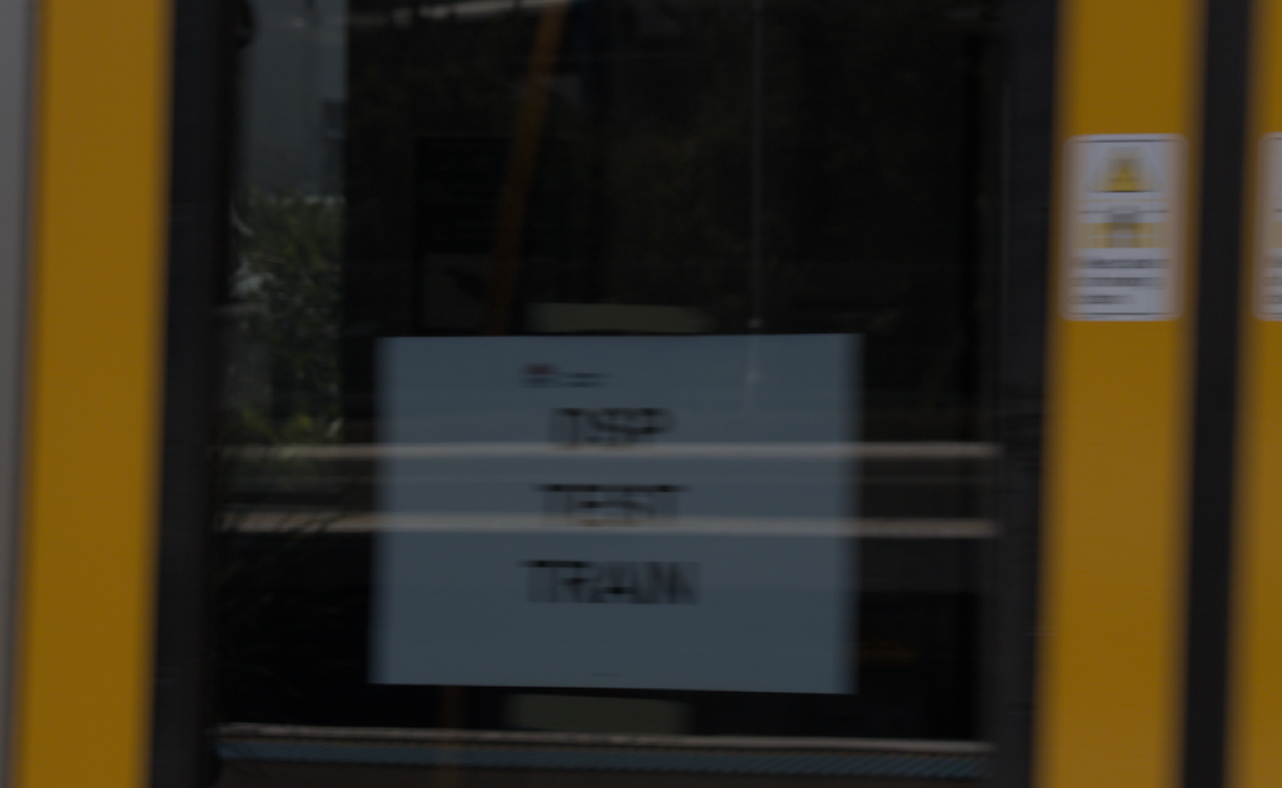 Close up of the "DSP TEST TRAIN" notice affixed to the interior side of a moving train door