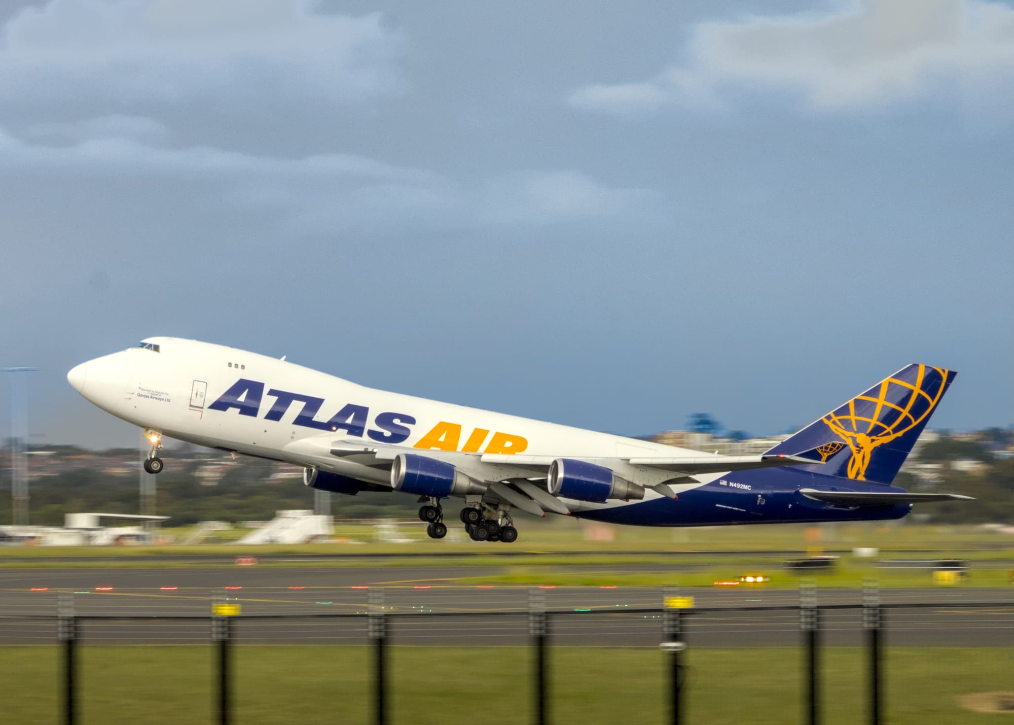 Atlas Air 747 cargo plane lifting off the runway under stormy skies, with the background motion blurred