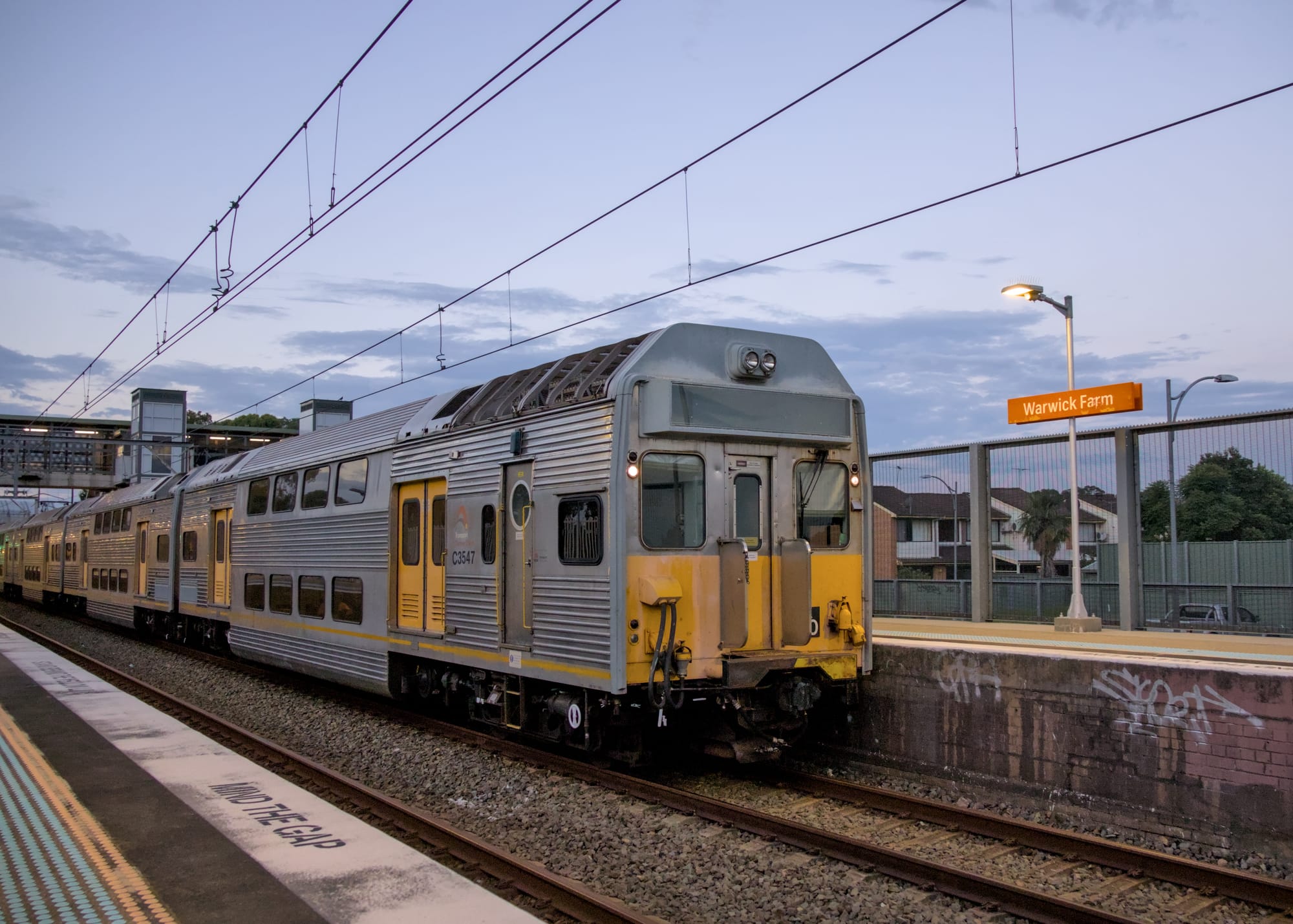 Silver K set stopped beside a well-lit platform at dusk