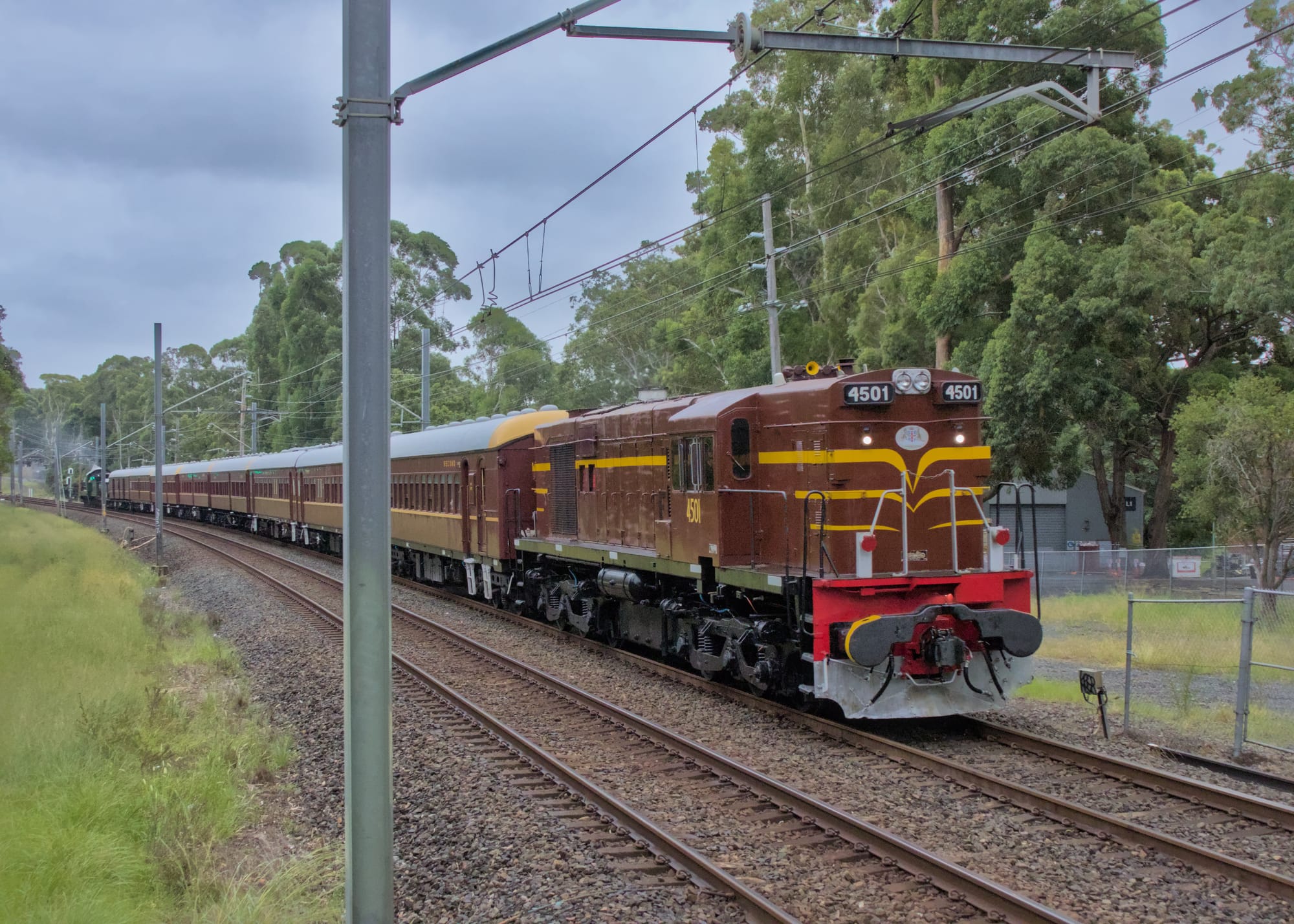 Maroon coloured heritage diesel locomotive hauls the train around a curve