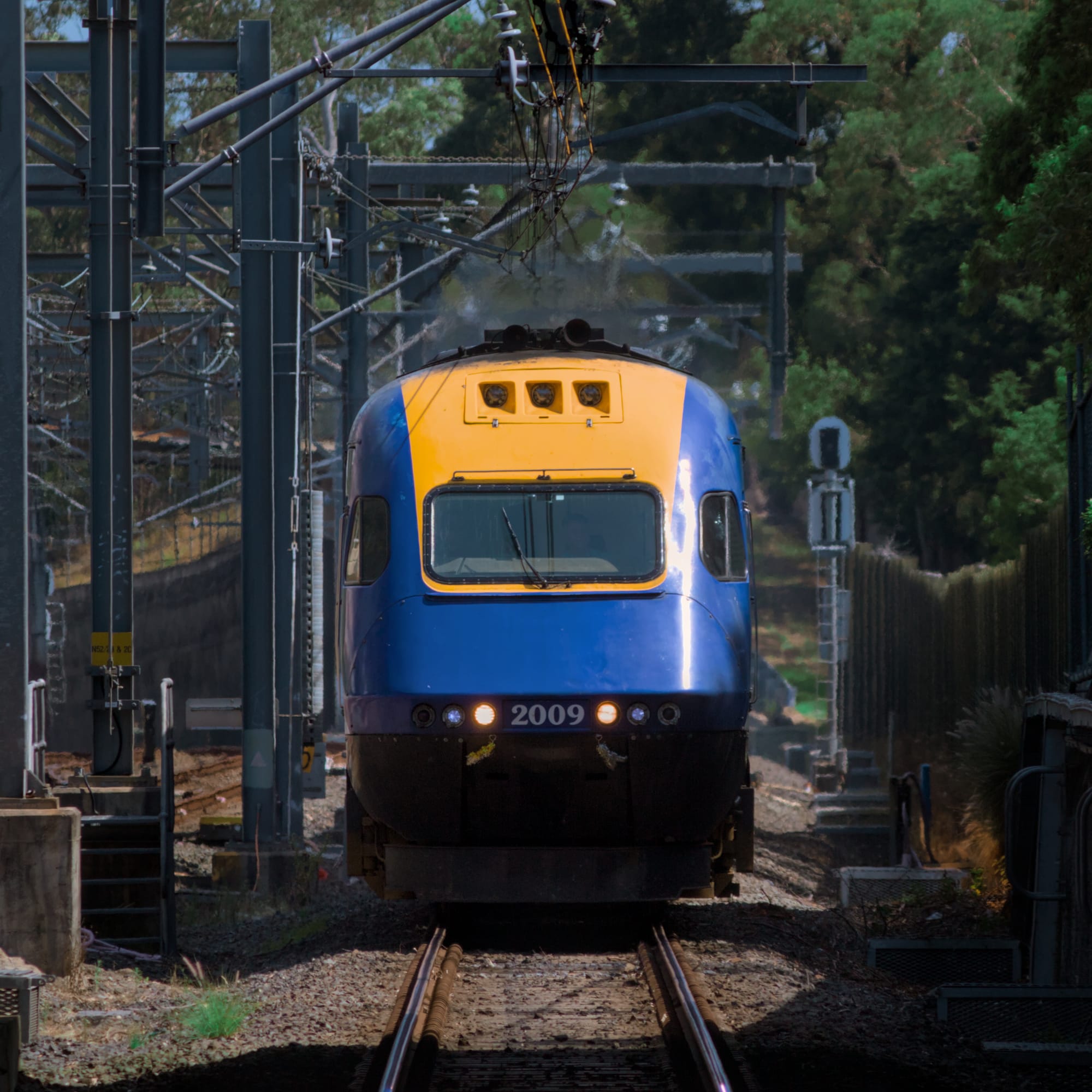 Dim front-on photo of XP 2009 in its original yellow and blue livery, with the light falling on the front of the train